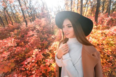 sonbahar arka plan üzerinde siyah şapkalı kadın bırakır.