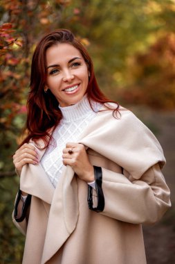 sarı sonbahar yaprakları bir arka plan üzerinde bej bir palto kadında