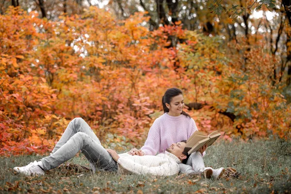 Sonbahar parkta oturan ve kitap okuma aşık çift — Stok fotoğraf