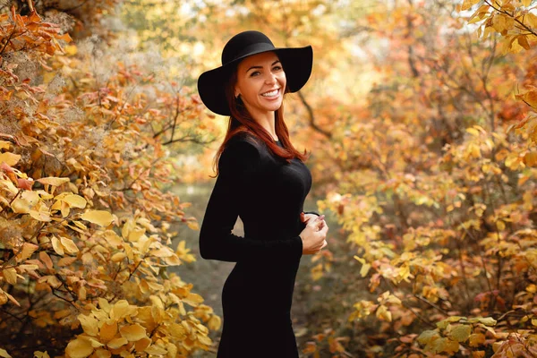 Mulher em vestido e chapéu no fundo da folhagem de outono — Fotografia de Stock