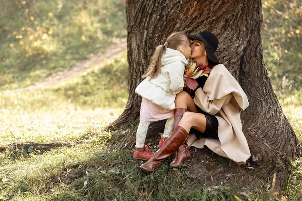 Matka, całując jej córka dziewczynka w pobliżu drzewa — Zdjęcie stockowe