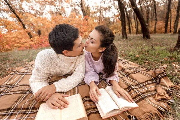 Casal apaixonado sentado no parque de outono e livro de leitura — Fotografia de Stock