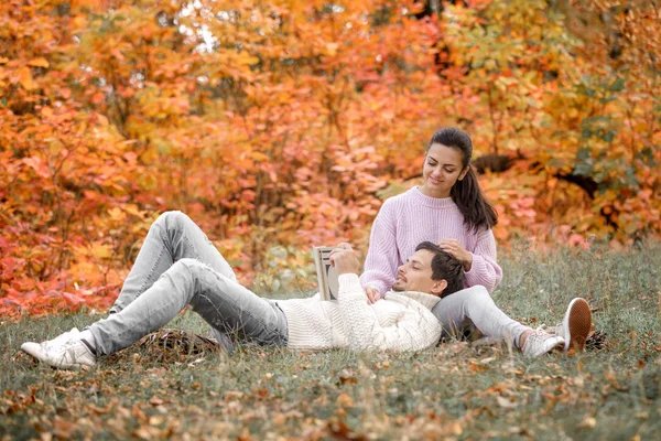 Couple in love sitting in autumn park and reading book — Stock Photo, Image