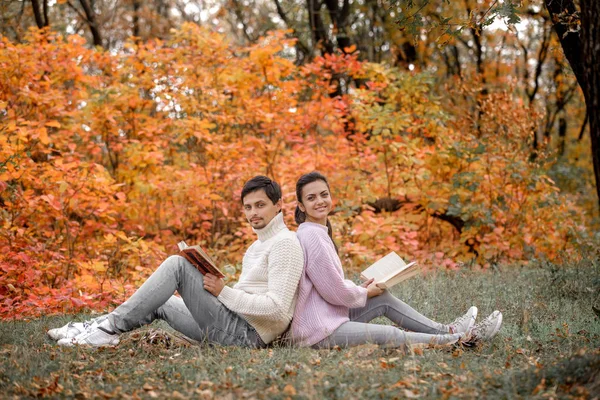 Pár v lásce sedící v podzimním parku a čtení knihy — Stock fotografie