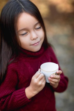 küçük kız sonbahar Park'ta sıcak çay içme
