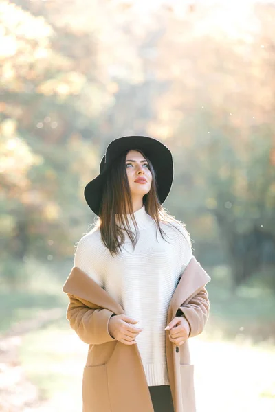 Hermosa joven con abrigo y sombrero negro en el parque — Foto de Stock