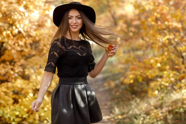 Bela mulher em vestido preto e chapéu no outono — Fotografia de Stock