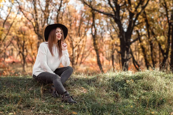 Hermosa mujer sentada en la hierba en el soleado día de otoño . — Foto de Stock