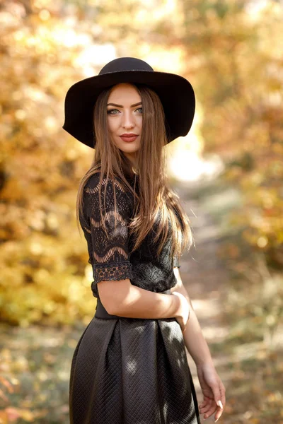 Mooie vrouw in zwarte jurk en muts in de herfst — Stockfoto