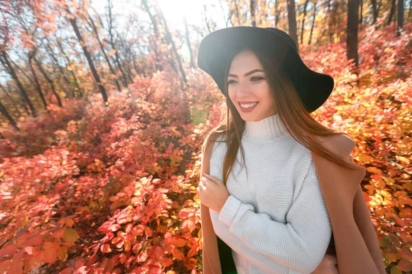 Woman in black hat on background of autumn leaves. — Stock Photo, Image
