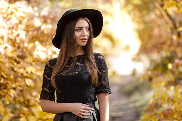 Mooie vrouw in zwarte jurk en muts in de herfst — Stockfoto