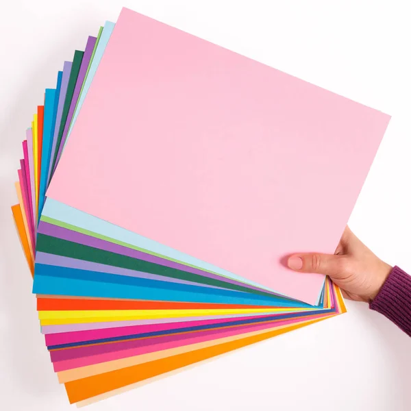 Ženská ruka drží listy různých barevného papíru. — Stock fotografie