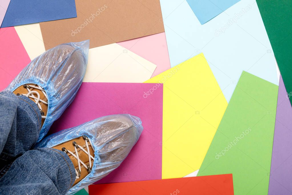 mens feet in shoe covers on multi-colored paper sheets