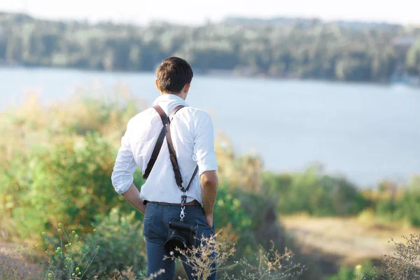 Male photographer with a digital camera is standing back — Stock Photo, Image