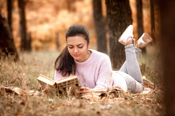妇女坐在秋天的公园和阅读书籍 — 图库照片