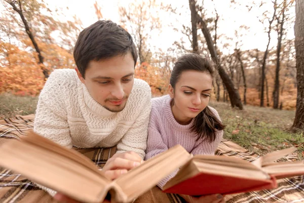 Couple in love sitting in autumn park and reading book — Stock Photo, Image