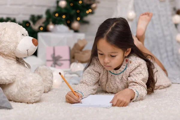 Söta barn flicka skriva brev till jultomten hemma — Stockfoto