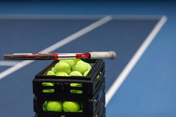 Låda med tennisbollar och tennisracket på tennisbanan — Stockfoto