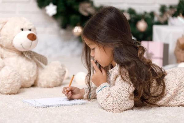 Söta barn flicka skriva brev till jultomten hemma — Stockfoto