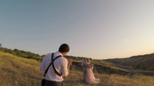 Свадебный фотограф фотографирует жениха и невесту — стоковое видео