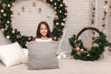 Yastık Noel çelenk evde arka plan üzerinde şirin mutlu çocuk kızla. metin için bir yer olarak yastık