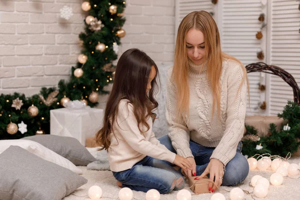 Мати і дитина дівчина упаковують різдвяні подарунки вдома . — стокове фото