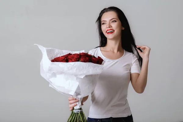 Hermosa joven con un gran ramo de rosas rojas — Foto de Stock