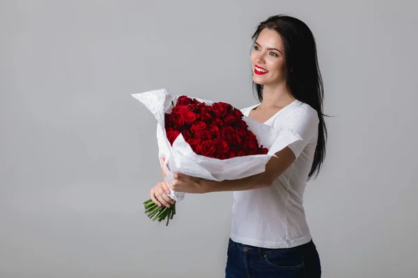 Hermosa joven con un gran ramo de rosas rojas —  Fotos de Stock