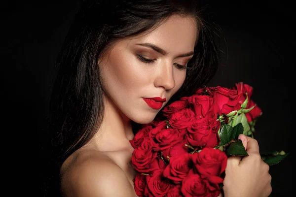 Όμορφη νεαρή γυναίκα με ένα μεγάλο μπουκέτο από κόκκινα τριαντάφυλλα — Φωτογραφία Αρχείου