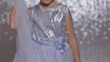 küçük kız çocuk gümüş bokeh arka plan üzerinde dans gümüş elbisenin içinde.