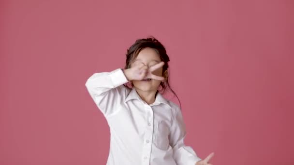 Petite fille en chemise blanche dansant sur fond rose . — Video