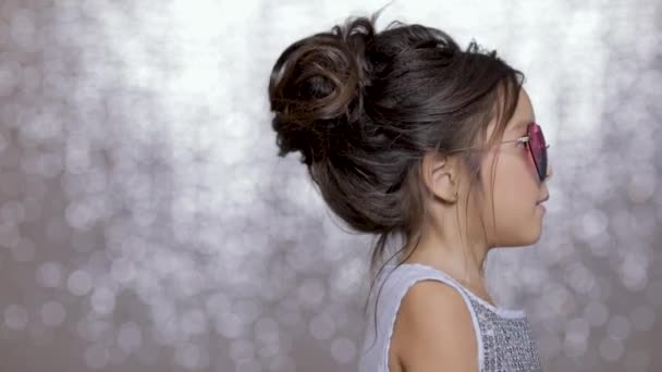 可爱快乐的小女孩在银色礼服和太阳镜跳舞的背景下 银波克 节日和庆祝活动 — 图库视频影像