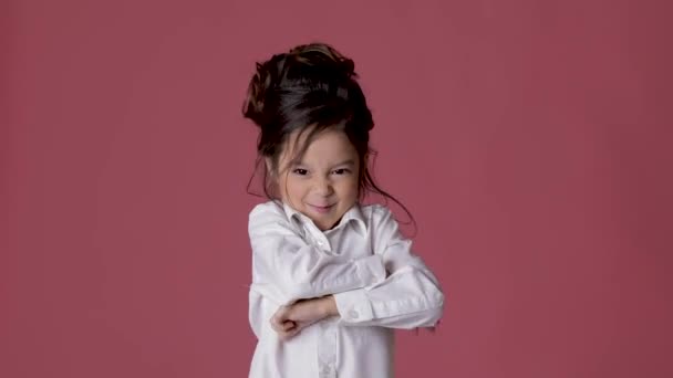 Cute little child girl in white shirt shows different emotions on pink background. — Stock Video