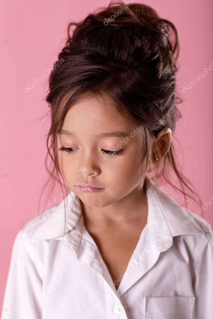 offended sad bored little girl in white shirt on pink background. Human emotions and facial expression