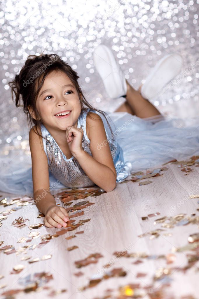 little girl in blue dress sitting on the floor with confetti