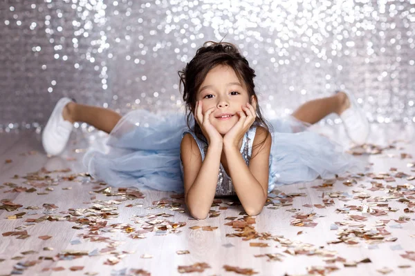 Маленька дівчинка в блакитній сукні сидить на підлозі з конфетті — стокове фото