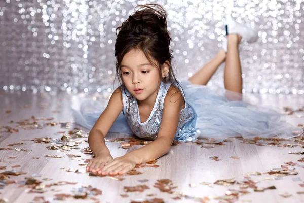 Little girl in blue dress sitting on the floor with confetti — Stock Photo, Image