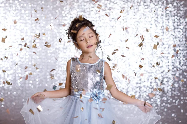 Mosolygó kis gyermek lány ezüst ruha konfetti háttér — Stock Fotó