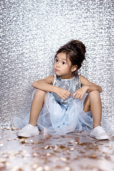 Pieni lapsi tyttö mekko istuu lattialla konfetti — kuvapankkivalokuva