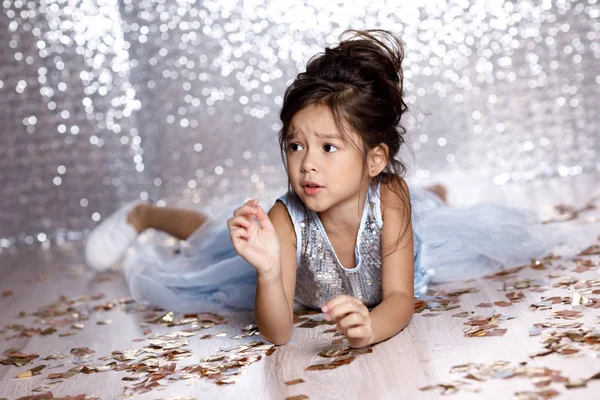 Little girl in blue dress sitting on the floor with confetti — Stock Photo, Image