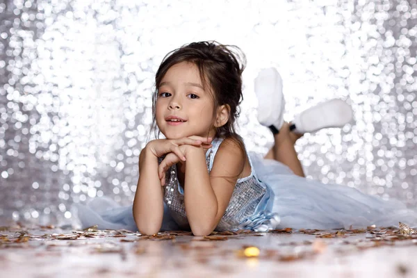 Little girl in blue dress sitting on the floor with confetti — Stock Photo, Image