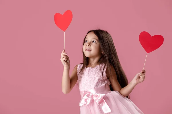 Mignonne petite fille dans une robe rose tenant un coeur en papier — Photo