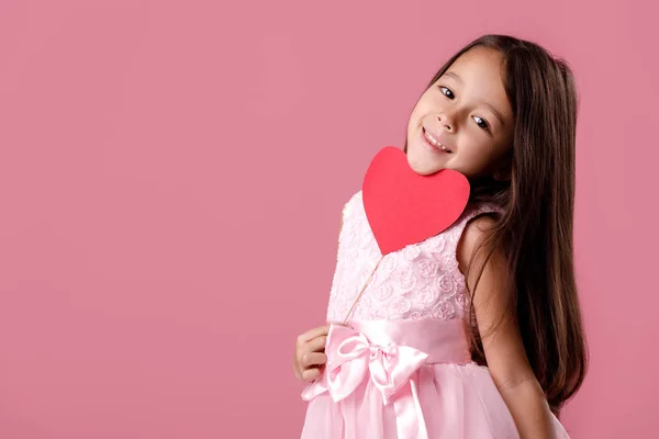 Милая маленькая девочка в розовом платье держит бумажное сердце — стоковое фото