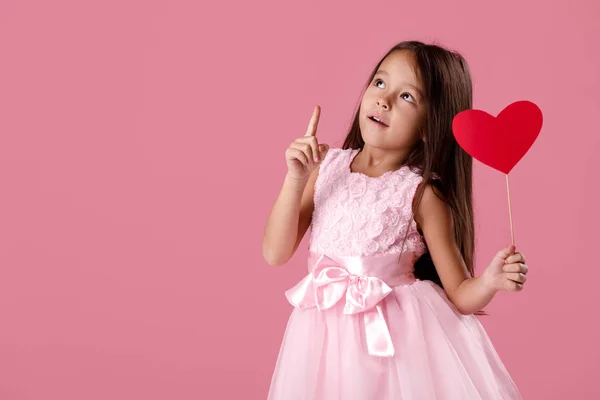 Mignonne petite fille dans une robe rose tenant un coeur en papier — Photo