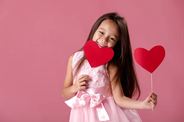 Niedliches kleines Mädchen in einem rosafarbenen Kleid mit einem Papierherz — Stockfoto