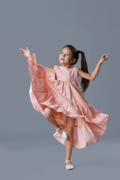 Menina em vestido rosa posando no fundo cinza. — Fotografia de Stock