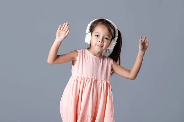 Bambina in abito e cuffie ascolta musica e balli — Foto Stock