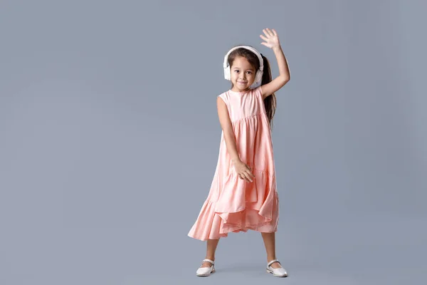Маленька дівчинка в сукні і навушники слухає музику і танці — стокове фото
