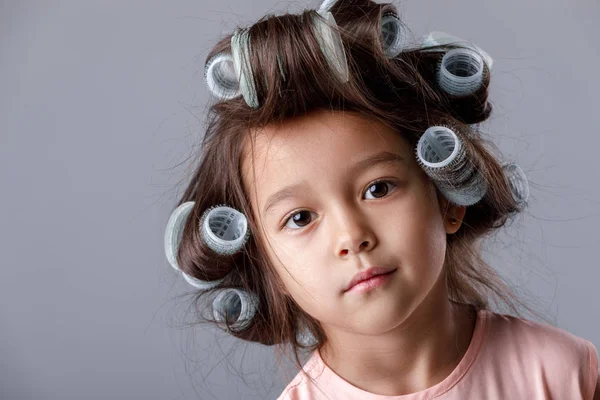 Cute little child girl in pink dress and hair curlers — Stock Photo, Image