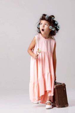 Lolipop tutan pembe elbise ve saç curlers içinde komik küçük kız